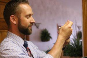 white man with blonde hair and beard (Nathan C Mortensen) looking at something in his hand at eye level